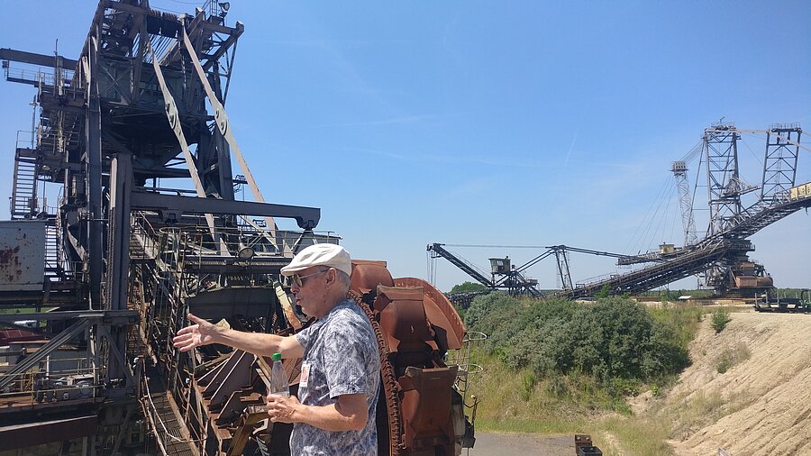 Ein Besucher steht neben den riesigen Baggerschafeln der Fördermaschine.