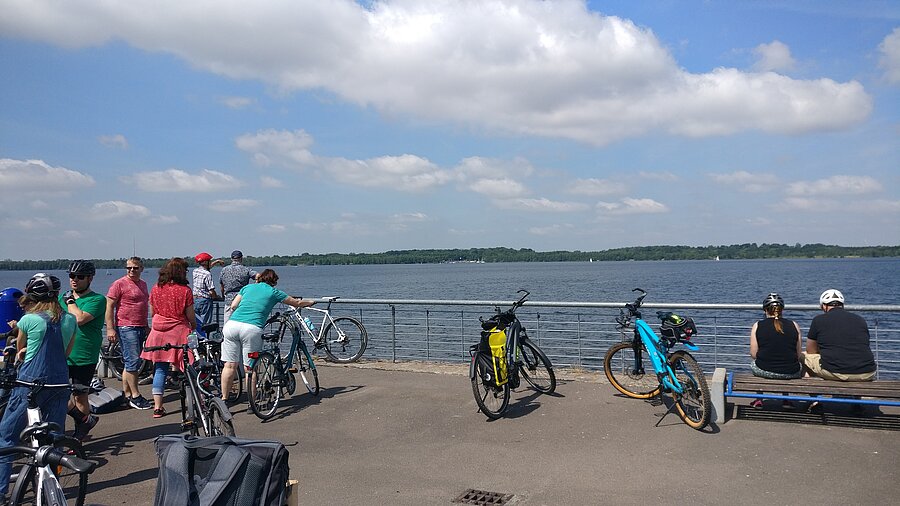 Besuchergruppe unterwegs im Neuseenland mit Blick auf einen See