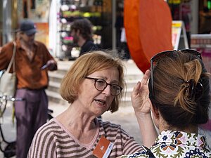 Vier Menschen unterhalten sich, dahinter ist das orangene Ohr zu sehen.